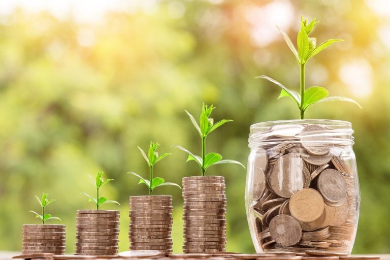 Piles of money with green shoots growing out of the top. The first pile of money is small and the piles increase in size left to right. he last one is a jam jar full of money!